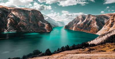 Beautiful turquoise lake surrounded by mountains in the valley of Russia, high resolution photography from Unsplash, shot on a Sony Alpha A7 IV camera, with professional color grading, a stunning landscape panoramic view. --ar 64:33