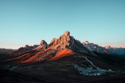 A mountain range in the Dolomites with a parking lot at sunset, DSLR photography, photo taken from above, in the style of Unsplash, panorama, Canon EOS R5 --ar 128:85