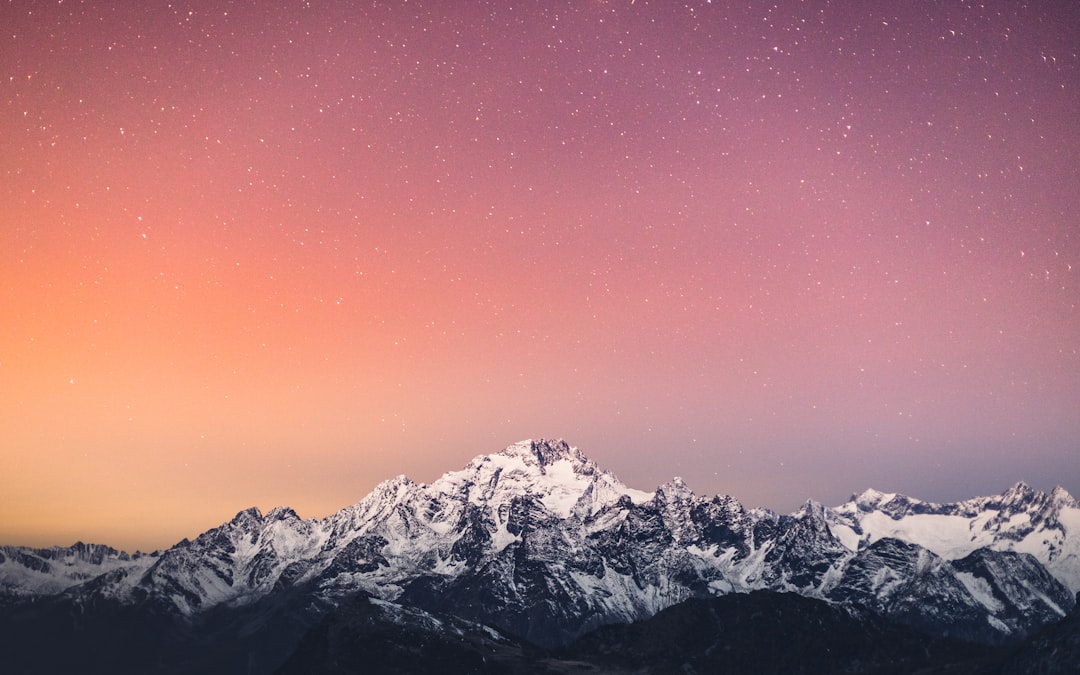 Starry sky over snowcapped mountains, pink and orange gradient background, high definition photography –ar 8:5