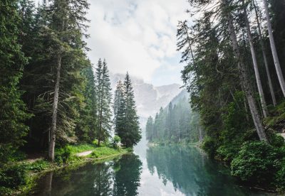 Beautiful lake in the forest with trees and mountains in the background. A natural landscape of Lago di braies, in the style of dol_helped 2086345978. photography --ar 16:11