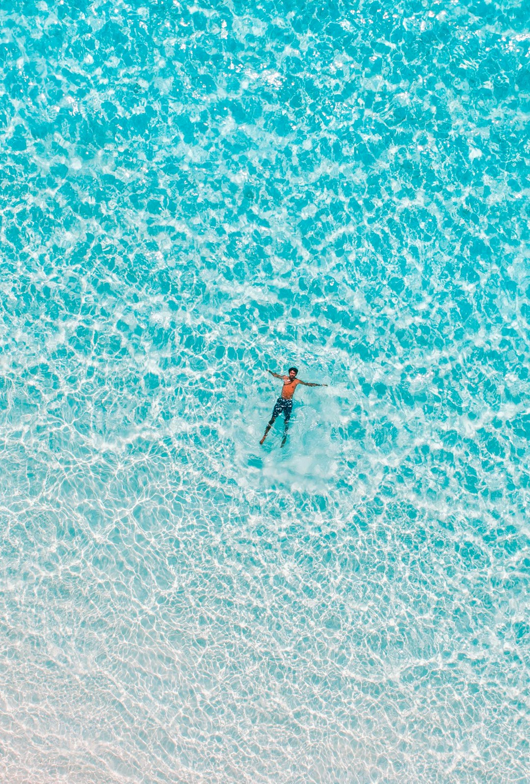 aerial view of surfer in the turquoise ocean, crystal clear water, minimalist photography, white sand beach. –ar 43:64