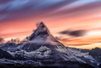 A dramatic sunset behind the majestic peak of Matterhorn mountain in Switzerland, with clouds swirling around it. High resolution photography in the style of professional colour grading, soft shadows, clean sharp focus HDR octane render. --ar 128:85