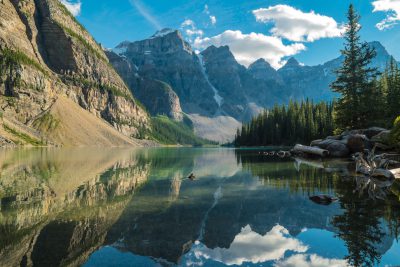 A serene mountain lake reflecting the surrounding peaks and trees, creating an idyllic scene of nature's beauty in Canada’s stunning burgundy mountains such as Moraine Lake. --ar 128:85