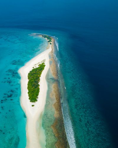 Aerial view of the Maldives, a long sand island with green jungle and turquoise ocean, National Geographic photography --ar 51:64