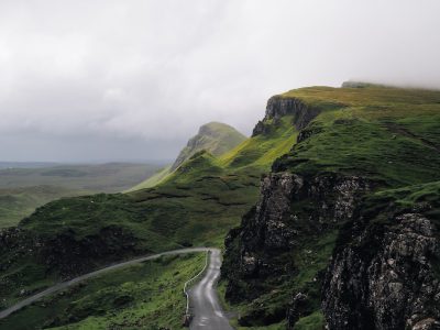 Photo of the Quiraing on Skye, an open road with green cliffs and misty clouds in the background, shot from above in the style of unsplash photography. --ar 4:3