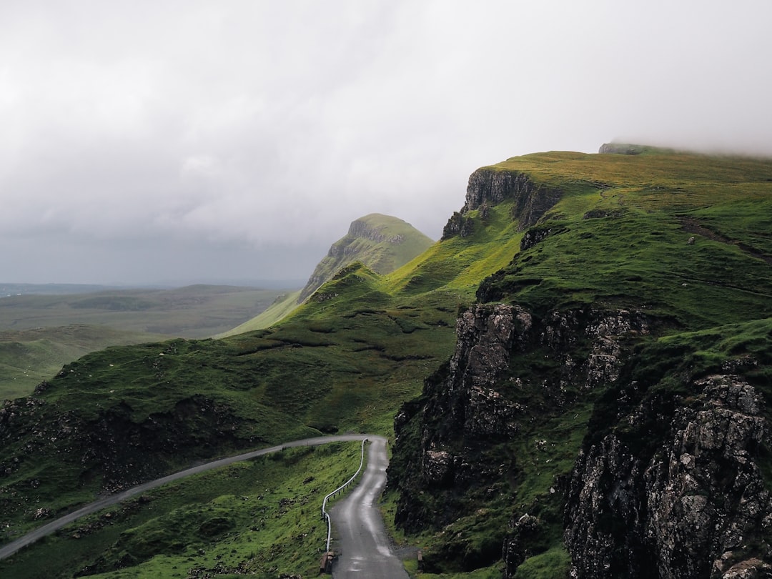 Photo of the Quiraing on Skye, an open road with green cliffs and misty clouds in the background, shot from above in the style of unsplash photography. –ar 4:3