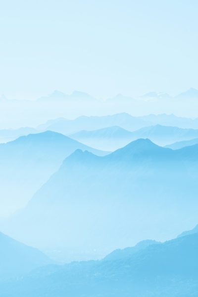 A light blue background with layers of mountains, creating an ethereal and dreamy atmosphere. The distant view showcases the vastness of nature, while the soft tones enhance tranquility. This photo was taken using a Canon EOS R5 mirrorless camera with a 24-70mm f/8 lens in the style of impressionist landscapes. --ar 85:128