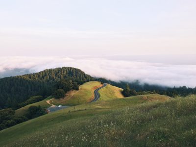 A view of the rolling hills and clouds at Golden Gate State Park, California, with some green grass on top, a road winding through the landscape, shot from above at a low angle in the style of Unsplash photography. --ar 4:3