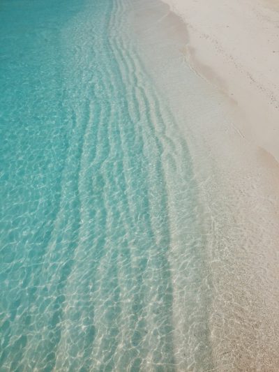 A photo of clear turquoise water and beach sand shot from above in the style of the Maldives. --ar 3:4