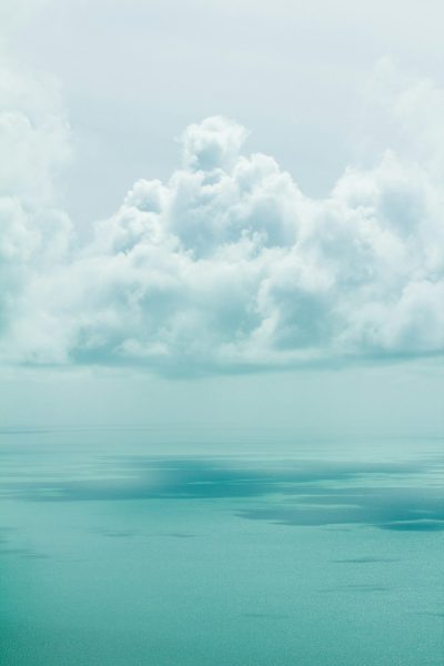 minimalist photo of the sea and clouds on the horizon, sky with teal color tones creating a calming effect. --ar 85:128