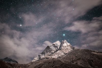 Starry night sky over the Himalayas, Ama Dabron mountain peak in earthen colors of white and gray with snow on top, clouds in the background, in the style of Nikon Z7 II, f/2 lens, starry composition. --ar 128:85