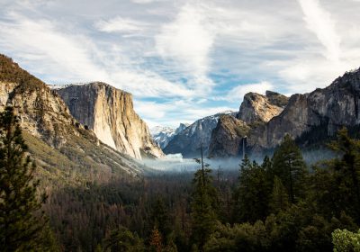 Yosemite National Park, California in the United States of America, showing El Capitan and Half Dome peak from tunnel view with trees and clouds in the background. Shot on Canon EOS C300 Mark III, 85 mm lens, cinestill 476 film in the style of cinestill. --ar 128:89