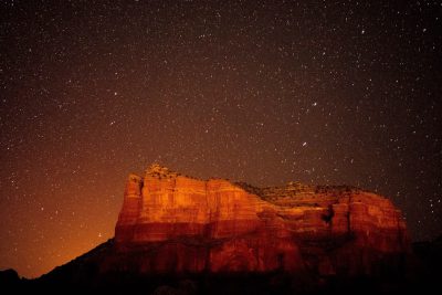 The red rocks of Sedona, Arizona at night with stars in the sky, beautiful, warm lighting. The photography is in the style of warm lighting. --ar 128:85