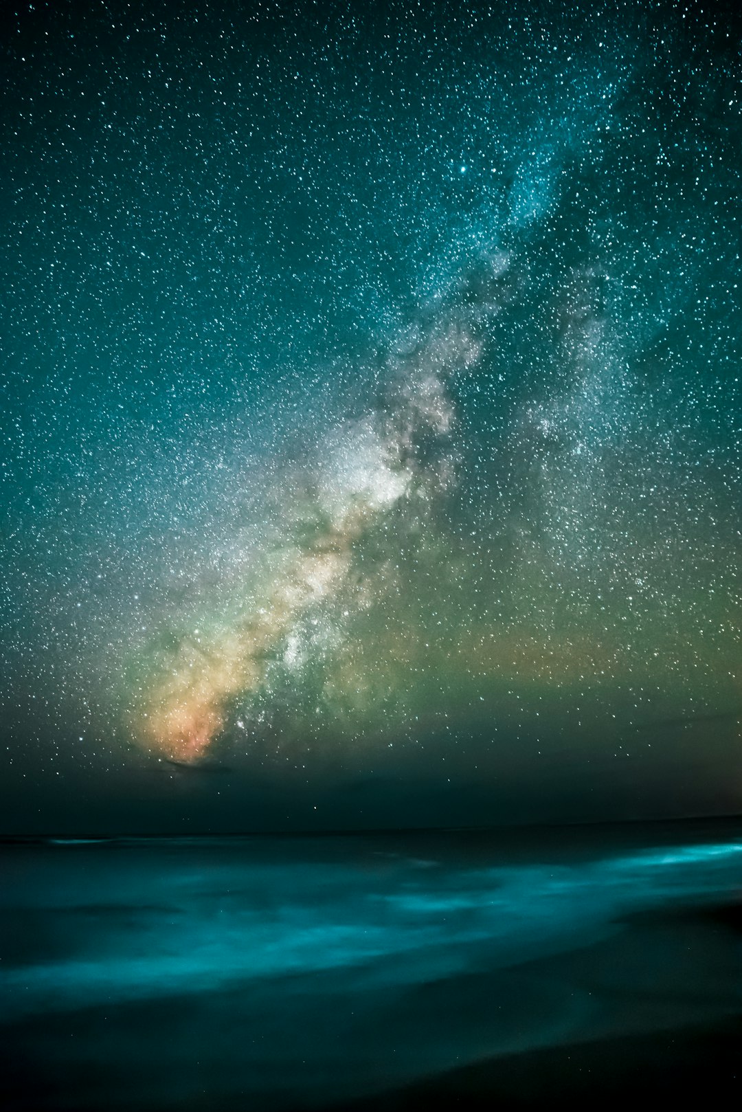 A long exposure photo of the Milky Way over an ocean in a starry night sky, with light painting in a dark teal and black color scheme. –ar 85:128