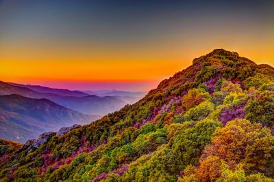 Colorful mountain landscape at sunrise in the style of J PCs of D&D, with colorful foliage on hills and mountains, a beautiful sky above. The scene is a view from atop Mount O, with high resolution photography, award winning photos, professional color grading, soft shadows, no contrast, and sharp focus in the digital photography style. --ar 128:85