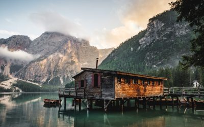 wooden cabin on the lake braies in dolomites in the style of seneryrutIREXqueladornbdüsseldorf blending natural colors and the beautiful mountains of south italy, with the green forest, wooden dock and boat at sunrise, stock photo, unsplash photography --ar 8:5