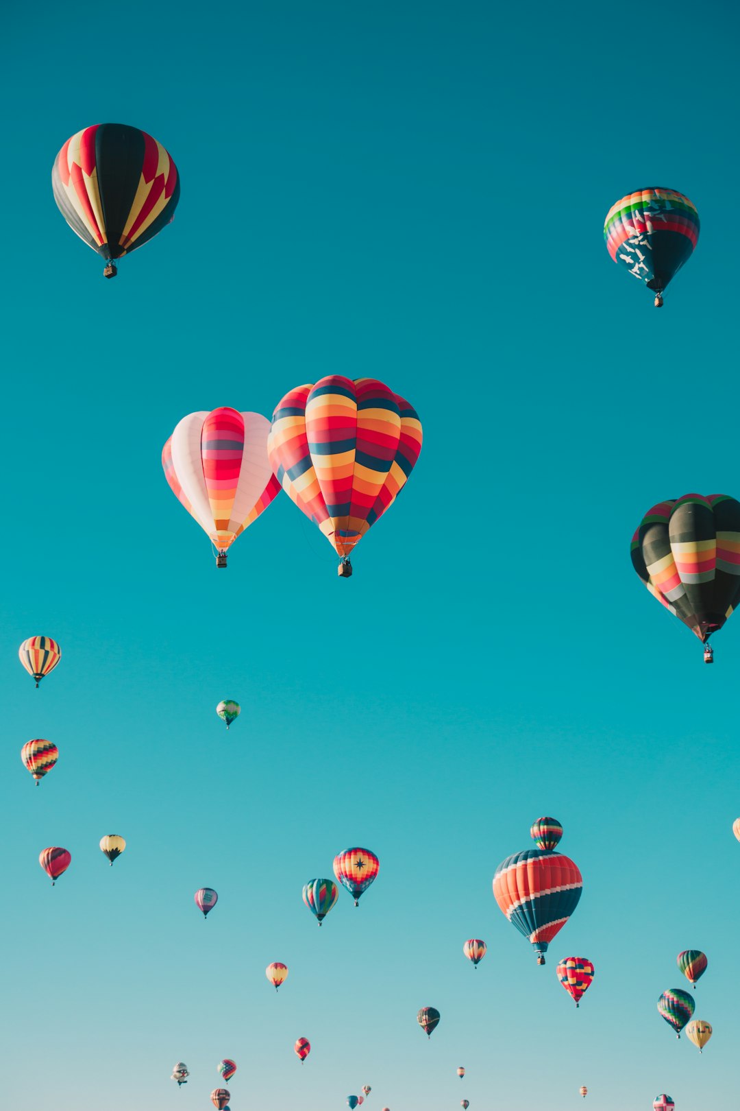 Photograph of multiple colorful hot air balloons flying in the clear blue sky, in the style of unsplash photography. –ar 85:128