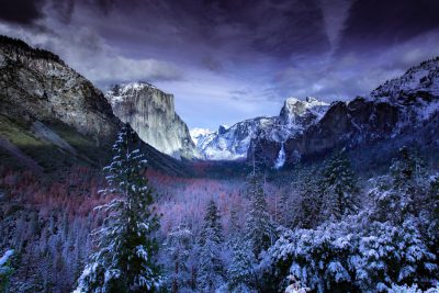 Yosemite National Park in winter, snow-covered trees and mountains under dark clouds, tunnel view with El Capitan in the background, high-resolution photography style, vivid colors, detailed textures of ice crystals on tree branches, serene atmosphere, dramatic lighting. --ar 128:85