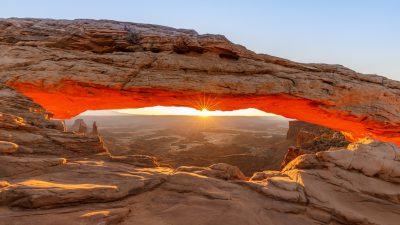 A beautiful sunrise at the Delicate Arch in Arches National Park, Utah with orange light shining through, captured in the style of Canon EOS R5 camera. --ar 16:9