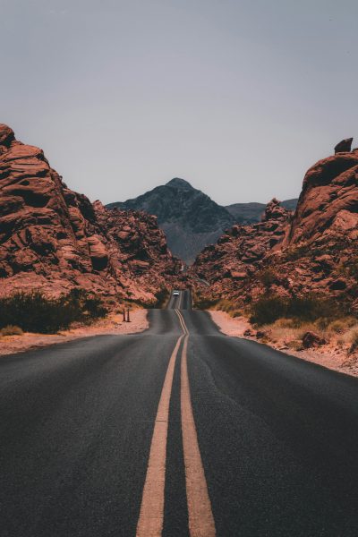 A straight road leads to the red rocks of the Valley of Fire in Nevada, in the style of unsplash photography. The style is minimalistic. --ar 85:128