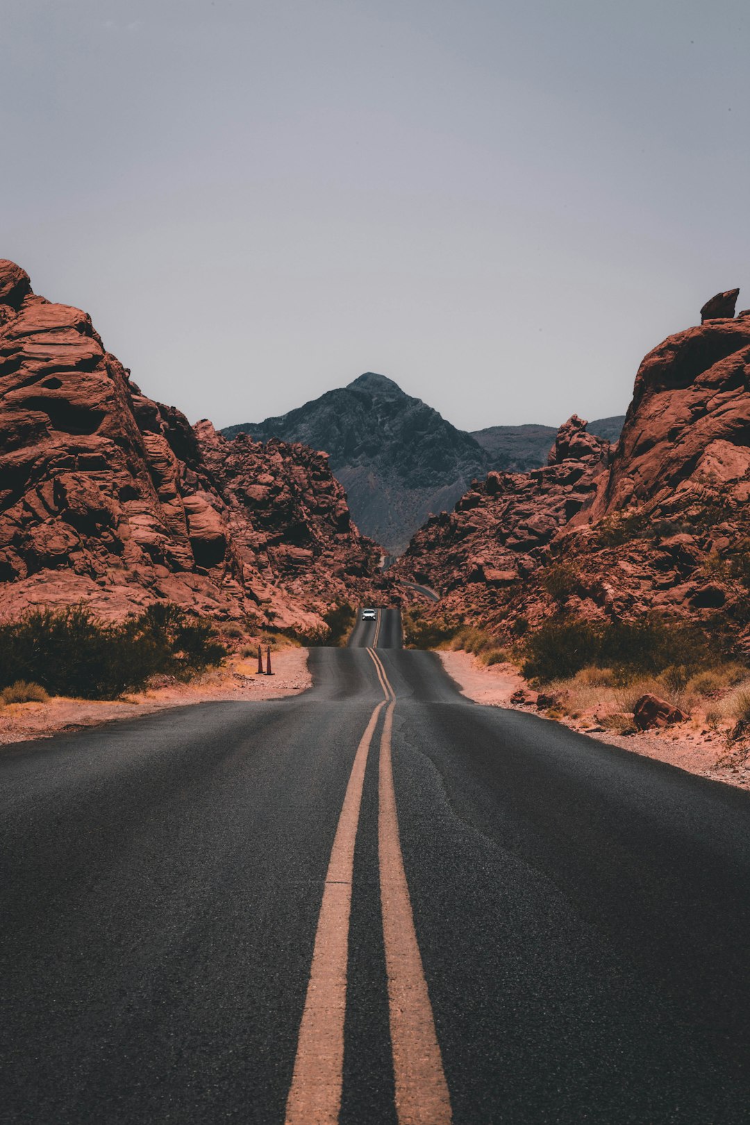 A straight road leads to the red rocks of the Valley of Fire in Nevada, in the style of unsplash photography. The style is minimalistic. –ar 85:128