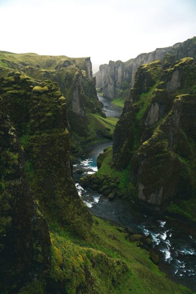 landscape photography of Fjarrarmetal in Iceland, a river running through the canyon with green mossy cliffs, shot in the style of Canon EOS R6 Mark II, unsplash style --ar 85:128