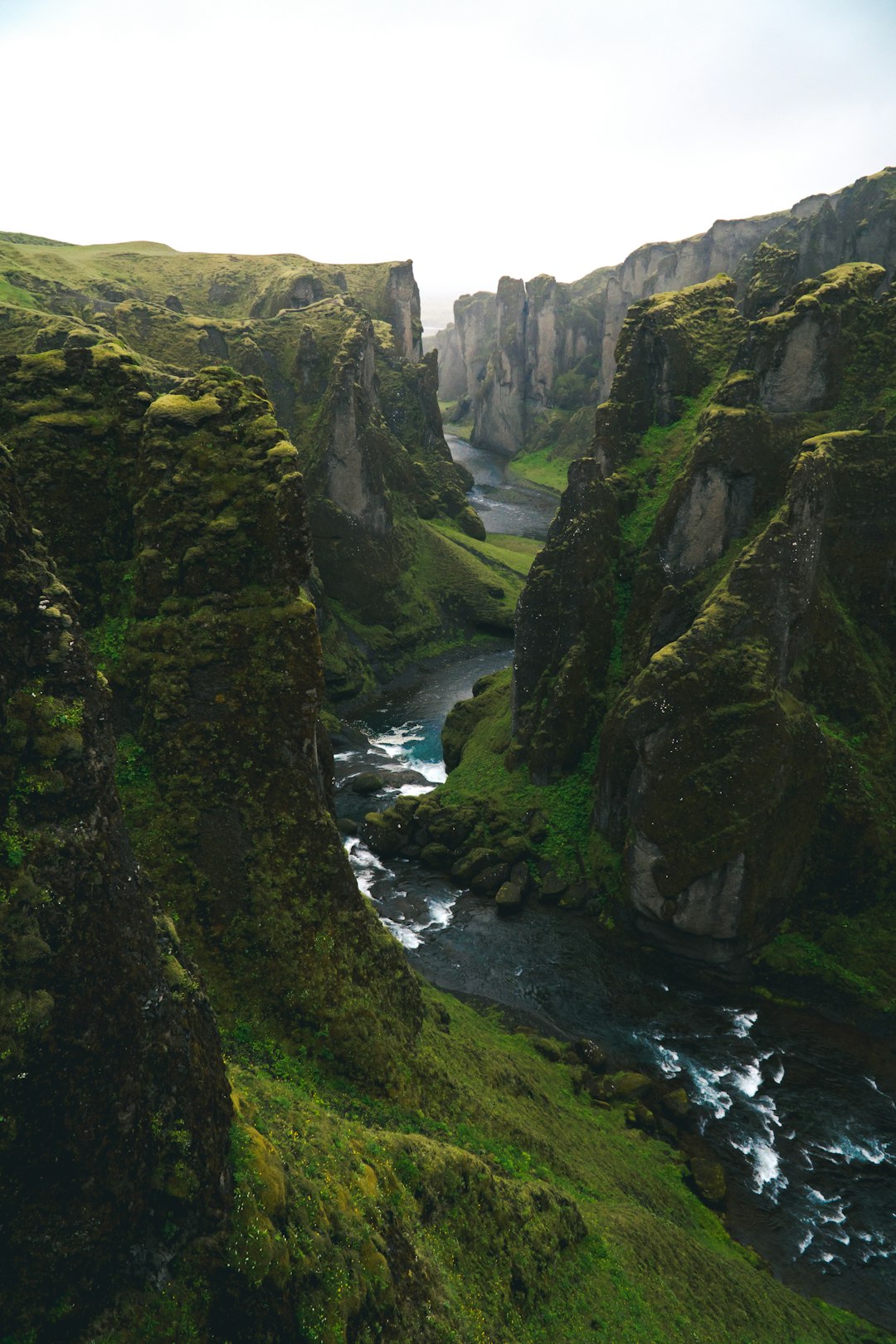 landscape photography of Fjarrarmetal in Iceland, a river running through the canyon with green mossy cliffs, shot in the style of Canon EOS R6 Mark II, unsplash style –ar 85:128